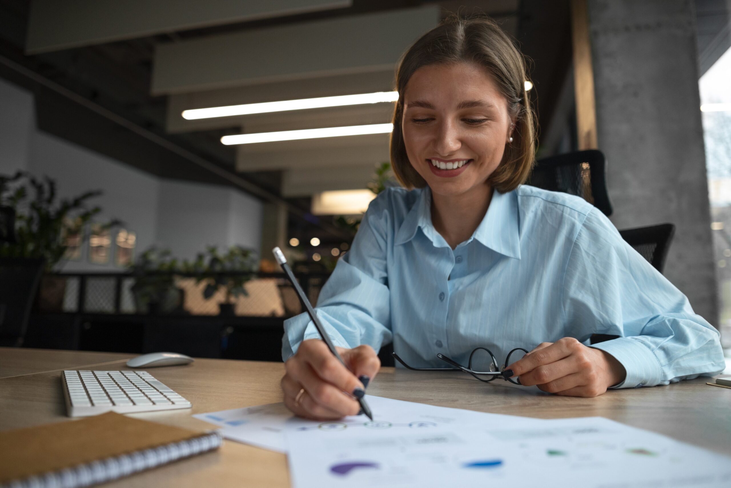 Professional woman at desk reviewing documents in a modern office – contact the Obsidian team today