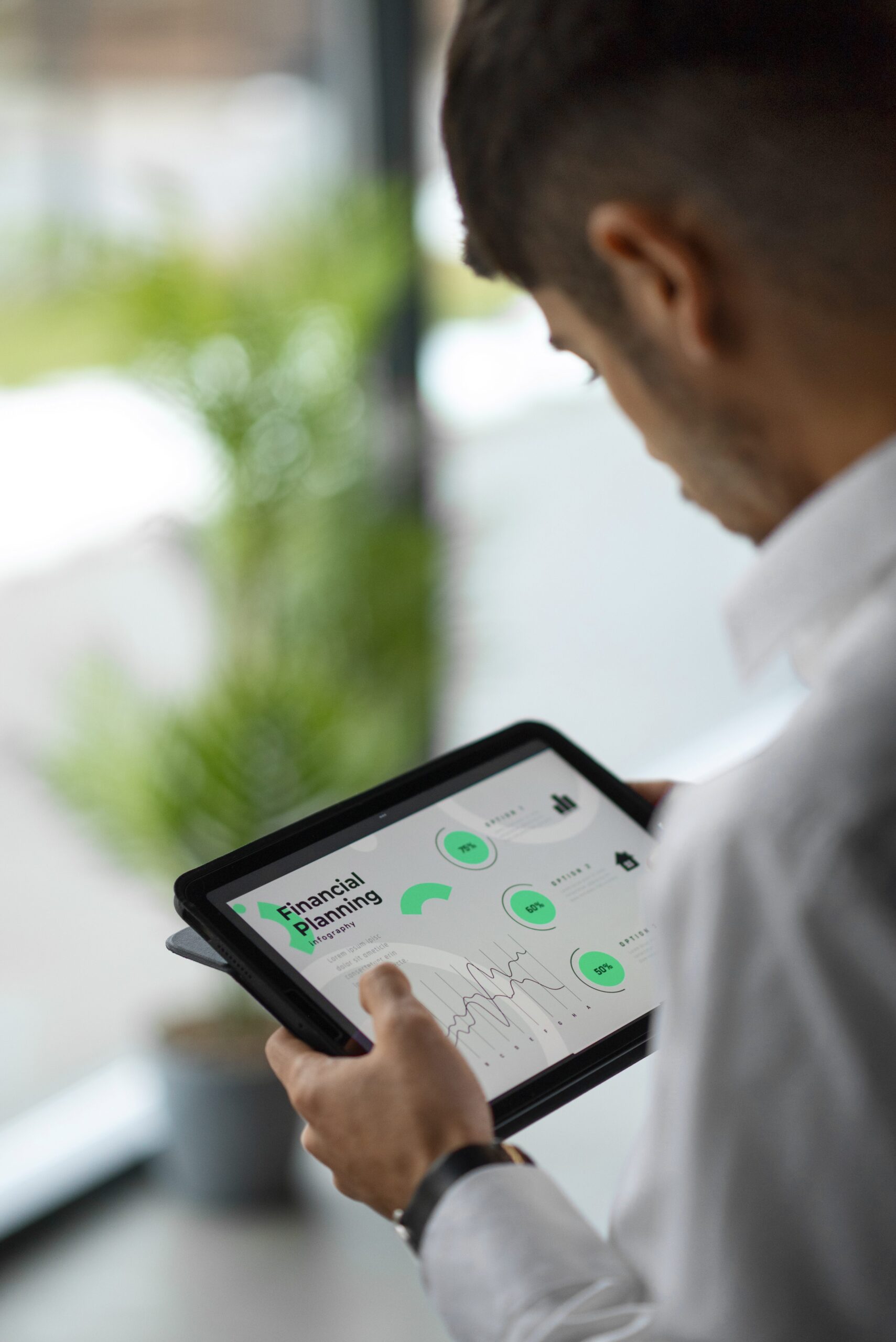 Man analyzing financial planning data on a digital tablet in a modern office environment